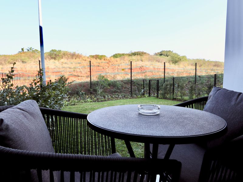 A covered patio area overlooking a private garden and perimeter fencing, providing a quiet outdoor space for relaxation.