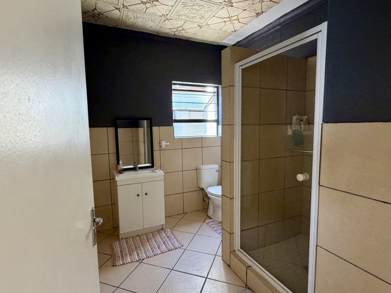 A functional bathroom featuring a shower enclosure, vanity cabinet, toilet, and tiled finishes with decorative ceiling detailing.