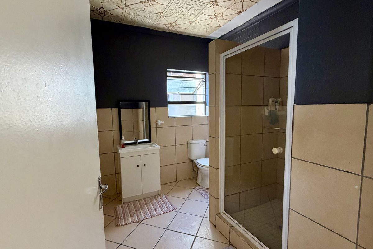 A functional bathroom featuring a shower enclosure, vanity cabinet, toilet, and tiled finishes with decorative ceiling detailing.