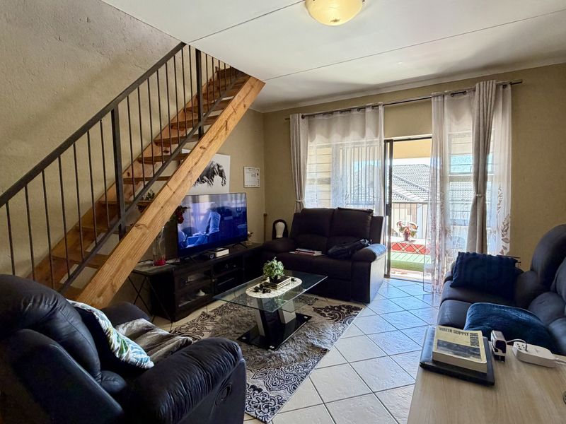 Living room featuring tiled flooring, a wooden staircase with metal balustrade, and a sliding glass door providing access to an outdoor balcony.