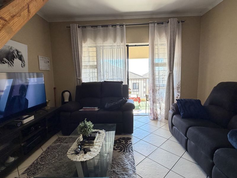 A living room featuring tiled flooring, a staircase, and a sliding glass door providing access to an outdoor balcony area.
