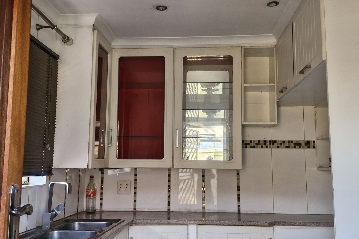 A functional kitchen area featuring built-in cabinetry, a stainless steel sink, granite countertops, and a decorative tiled backsplash.