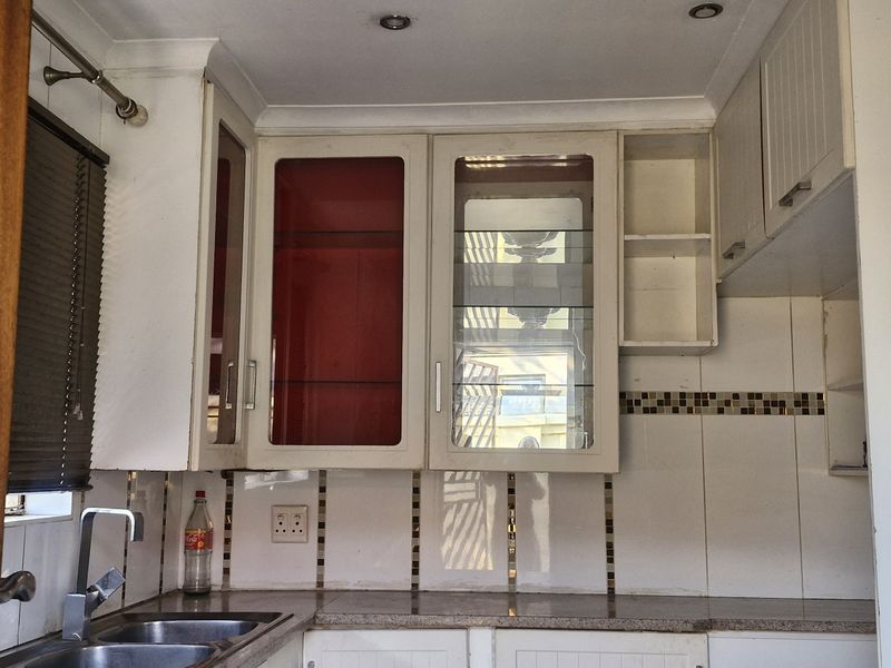 A functional kitchen area featuring built-in cabinetry, a stainless steel sink, granite countertops, and a decorative tiled backsplash.
