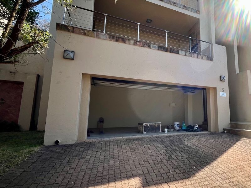 Front elevation of a multi-story residence featuring a paved driveway, double garage, and an upper-level balcony with stainless steel railings.
