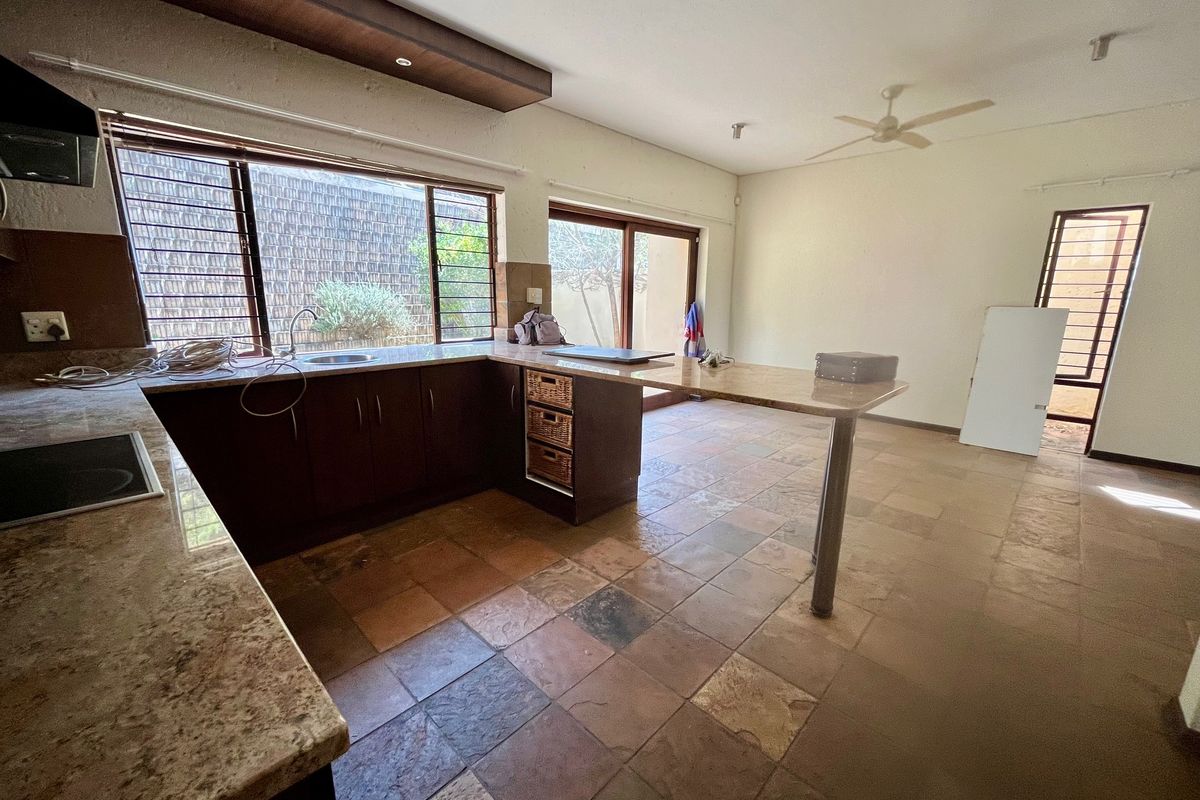 Spacious kitchen featuring granite countertops, ample built-in cabinetry, tiled flooring, and direct access to the outdoor area through sliding glass doors.