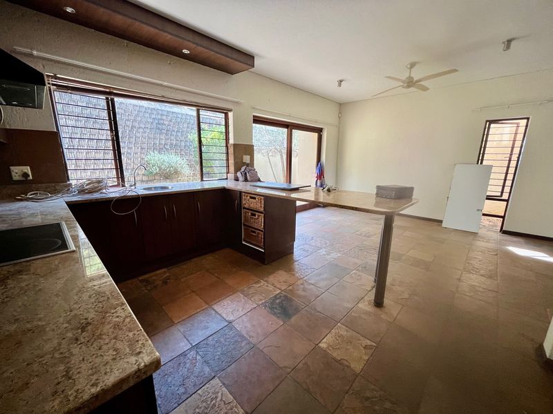 Spacious kitchen featuring granite countertops, ample built-in cabinetry, tiled flooring, and direct access to the outdoor area through sliding glass doors.