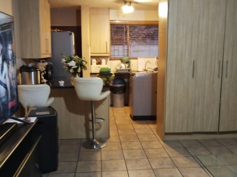 Open plan living and kitchen area featuring tiled flooring, built-in cabinetry, and a functional kitchen layout with integrated sink and counter space.