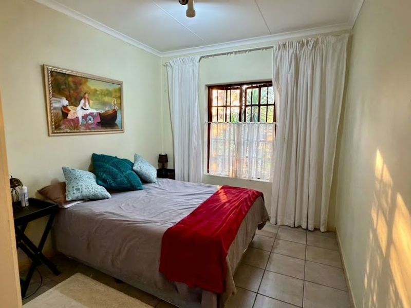 A functional bedroom featuring tiled flooring, a window with security bars, and coved ceiling detailing.