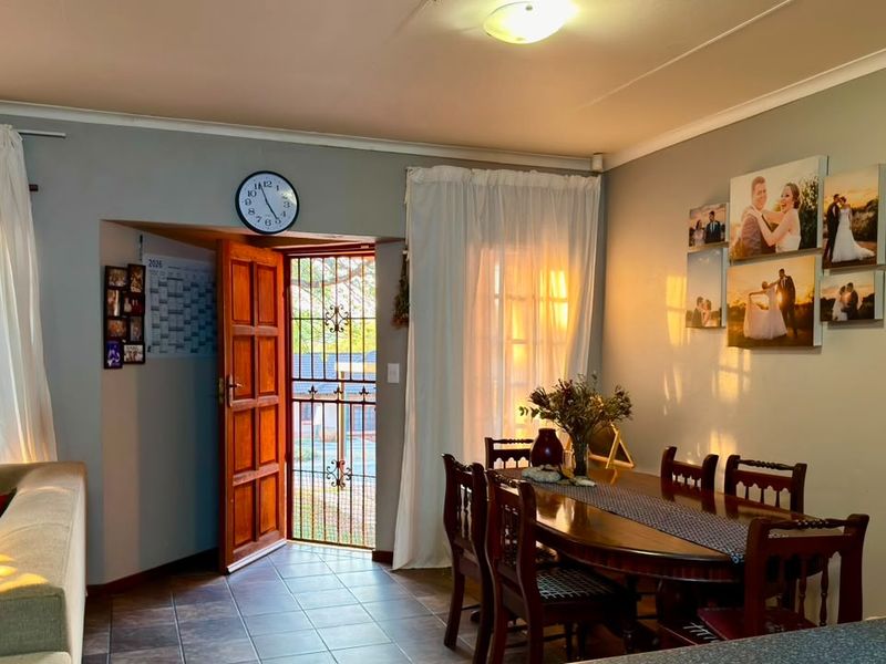 Open plan living and dining area featuring tiled flooring, natural light, and direct access to the exterior through a secure timber door.