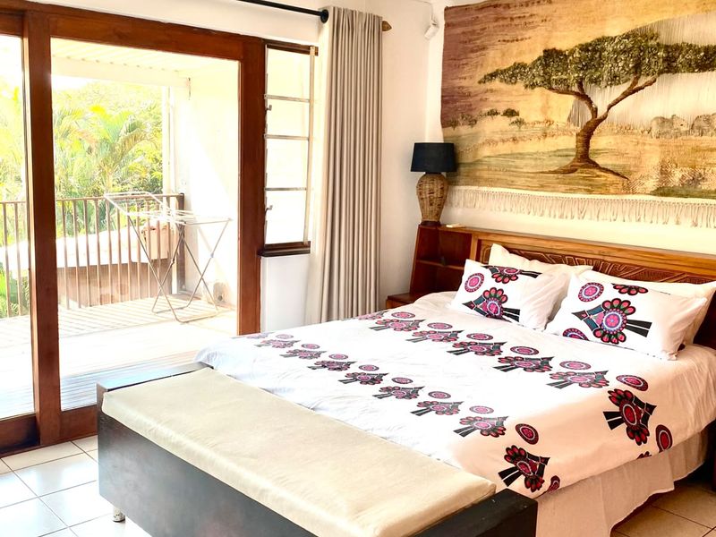 Bright bedroom featuring tiled flooring, a ceiling fan, and large sliding glass doors providing direct access to an outdoor balcony.