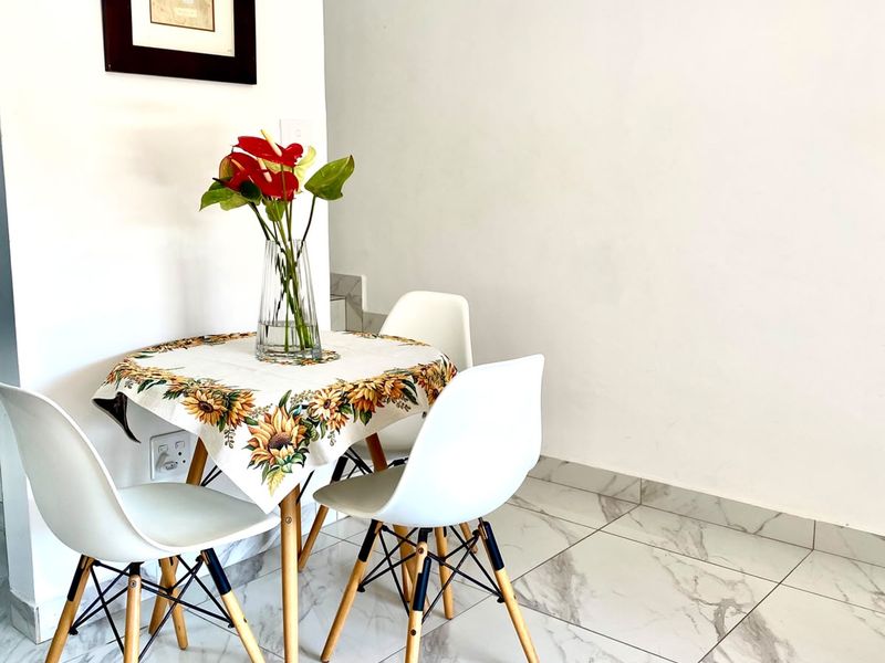 A bright dining area featuring modern marble-look porcelain floor tiles and clean white walls, providing a neutral and contemporary foundation for the space.