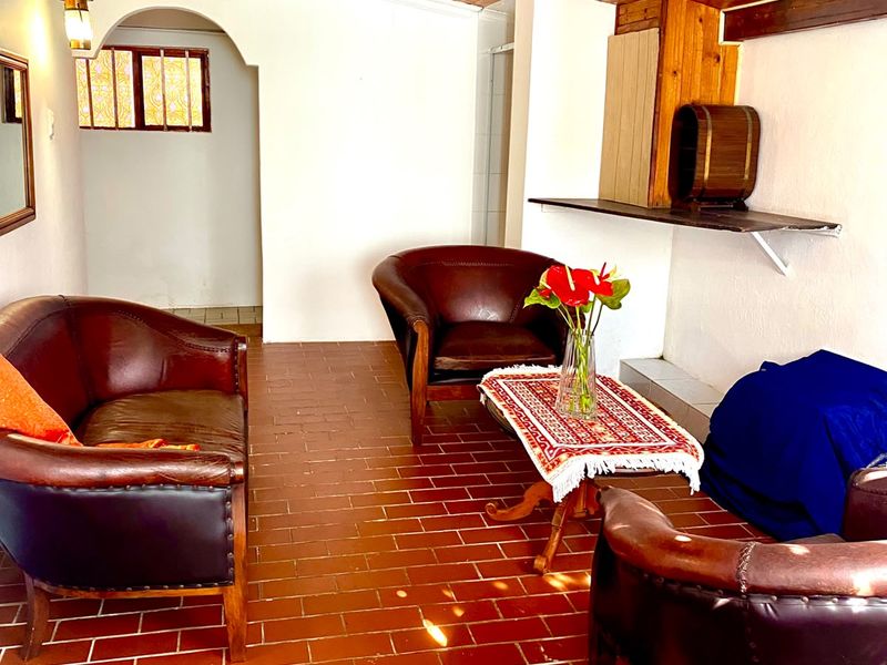 Covered patio area featuring a warm timber ceiling, terracotta tile flooring, and an arched entryway, providing a rustic and inviting outdoor living space.