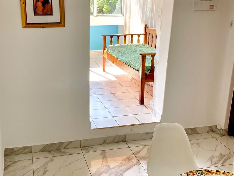 A bright living area featuring modern marble-look floor tiles and an arched doorway leading to an adjoining sunroom or balcony space.