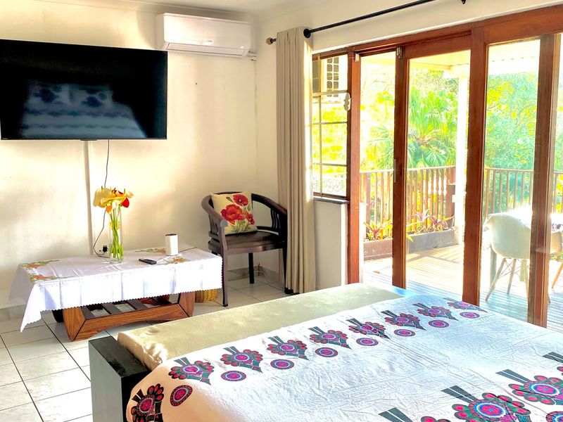 A bedroom featuring tiled flooring, a ceiling fan, split-system air conditioning, and sliding glass doors providing access to an outdoor balcony area.
