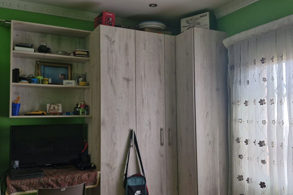 A bedroom featuring a light wood-grain built-in wardrobe and integrated shelving unit, complemented by crown molding and a ceiling fan.