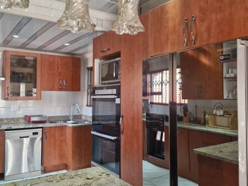 A functional kitchen featuring wooden cabinetry, granite countertops, built-in oven and microwave, and tiled flooring with modern pendant lighting.
