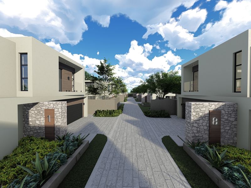 Modern residential complex entrance featuring paved driveway, stone-clad pillars, and contemporary architectural design with balconies.