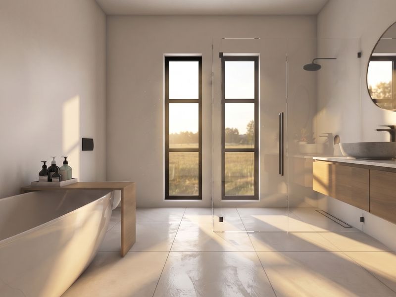 Modern, sunlit bathroom featuring a sleek freestanding bathtub, a spacious walk-in glass shower, and a contemporary wall-mounted vanity with a vessel sink.