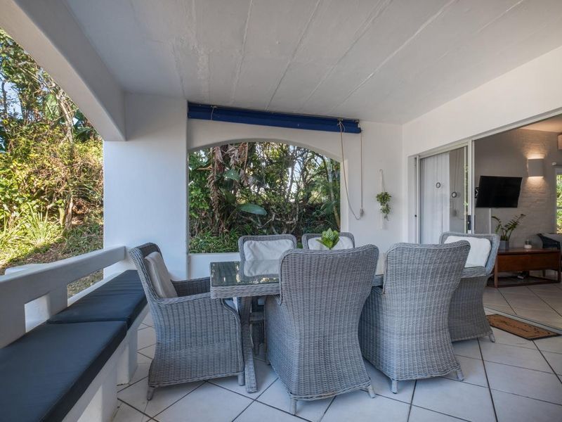 A covered patio area featuring tiled flooring, built-in bench seating, and direct access to the interior living space through sliding glass doors.