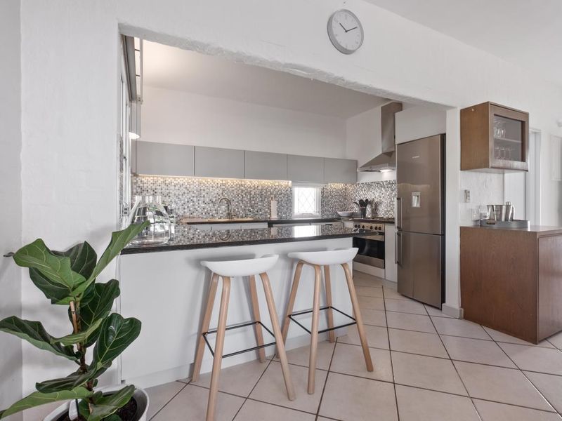 Open plan kitchen featuring granite countertops, mosaic tile backsplash, stainless steel appliances, and ceramic floor tiles, seamlessly connected to the living area.