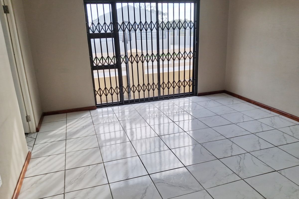 An empty living room featuring polished marble-look ceramic floor tiles and a secure sliding glass door leading to the exterior.