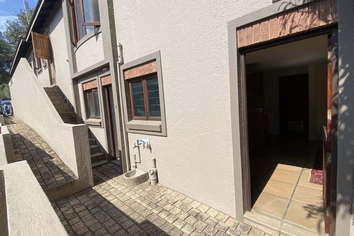 Rear exterior view showing a paved walkway, external staircase, and access to the interior through a tiled threshold.