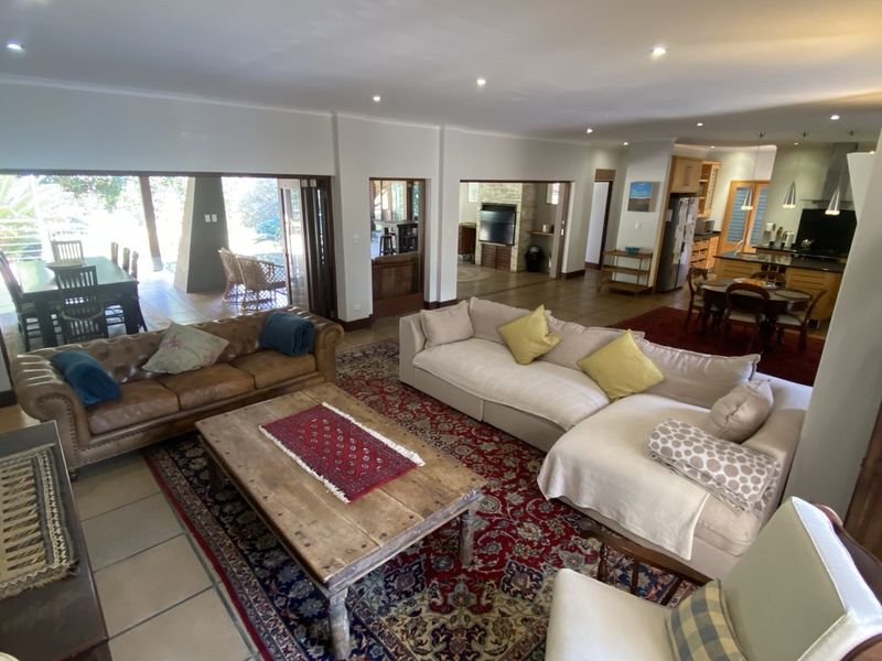 Spacious open-plan living area featuring tiled floors, recessed lighting, and seamless flow to an outdoor patio, with an integrated kitchen visible in the background.