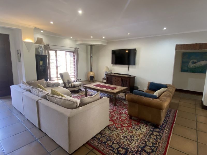 Spacious living room featuring tiled flooring, recessed downlighting, and a unique freestanding fireplace, offering a comfortable and well-lit area for relaxation.