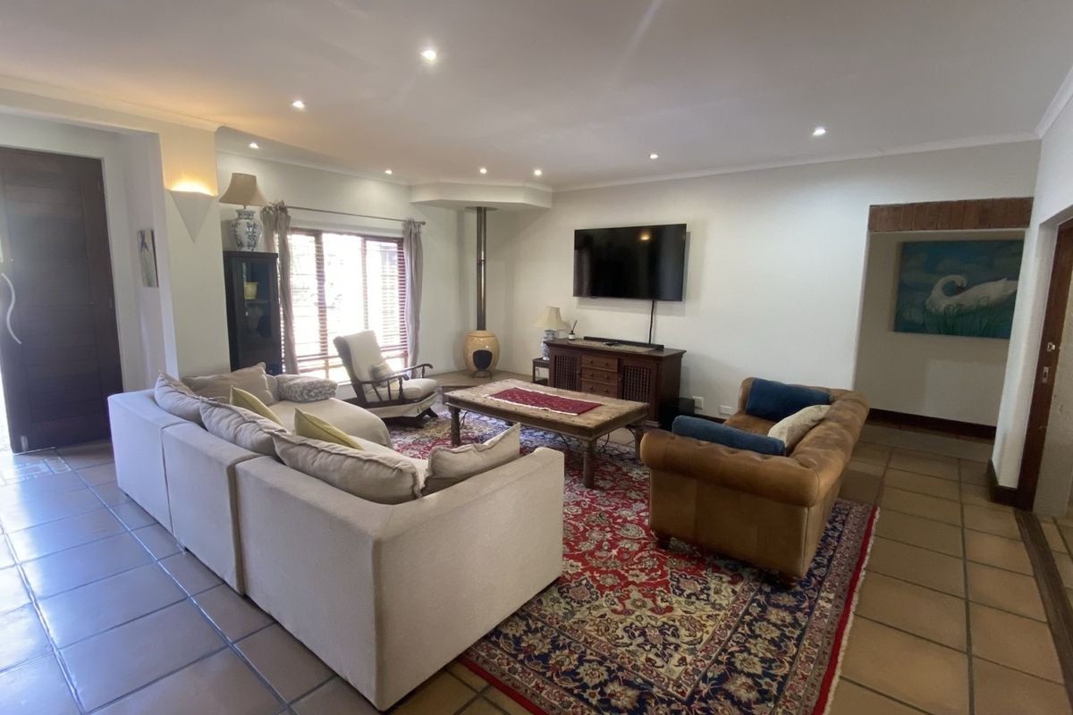 Spacious living room featuring tiled flooring, recessed downlighting, and a unique freestanding fireplace, offering a comfortable and well-lit area for relaxation.