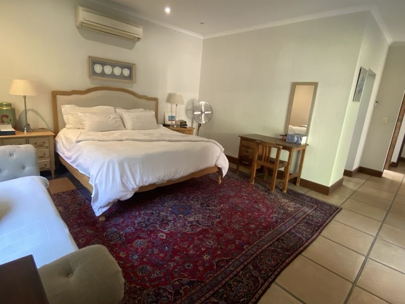 Spacious bedroom featuring tiled flooring, recessed downlighting, and a wall-mounted split-system air conditioning unit.