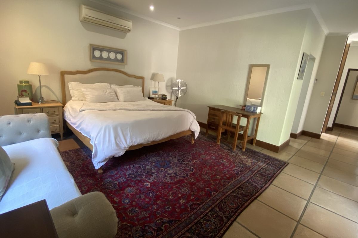 Spacious bedroom featuring tiled flooring, recessed downlighting, and a wall-mounted split-system air conditioning unit.
