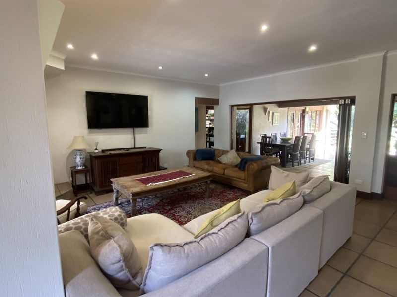 Spacious open-plan living area featuring tiled flooring, recessed downlighting, and large sliding glass doors providing seamless access to the outdoor dining space.