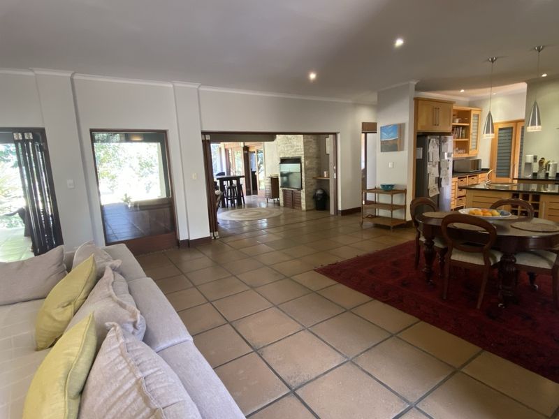 Spacious open-plan living and kitchen area featuring tiled floors, recessed lighting, a central kitchen island, and direct access to an outdoor patio.