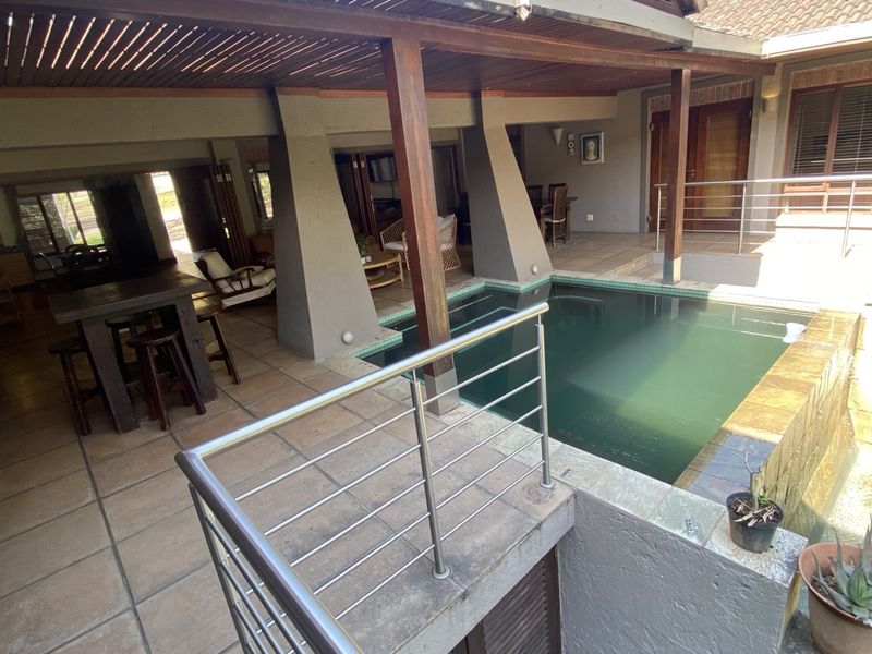 Covered outdoor patio area featuring a swimming pool with stainless steel balustrades and tiled flooring, ideal for entertainment.