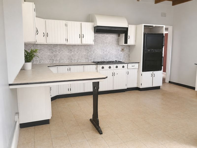 A functional kitchen featuring white cabinetry, a gas hob, built-in oven, and tiled backsplash, offering a clean and practical layout.