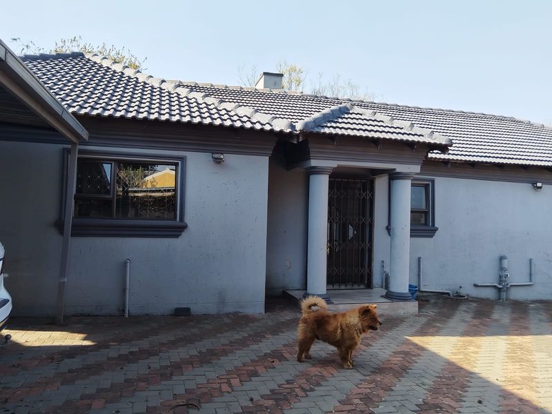 Front elevation of a single-story house featuring a tiled roof, concrete columns at the entrance, and a paved driveway.