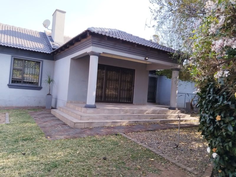 A rear view of the house featuring a covered patio with concrete columns, tiled flooring, and sliding glass doors leading into the home.