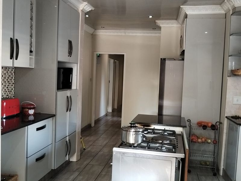 Modern kitchen featuring grey cabinetry, granite countertops, a gas hob, and tiled flooring with recessed lighting and decorative crown molding.