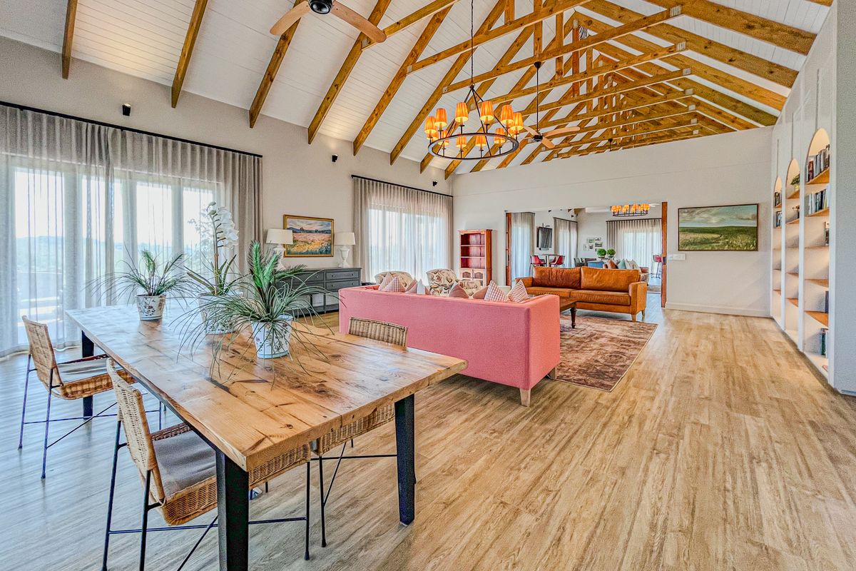 Spacious open-plan living and dining area featuring high vaulted ceilings with exposed timber trusses, built-in shelving, and abundant natural light.