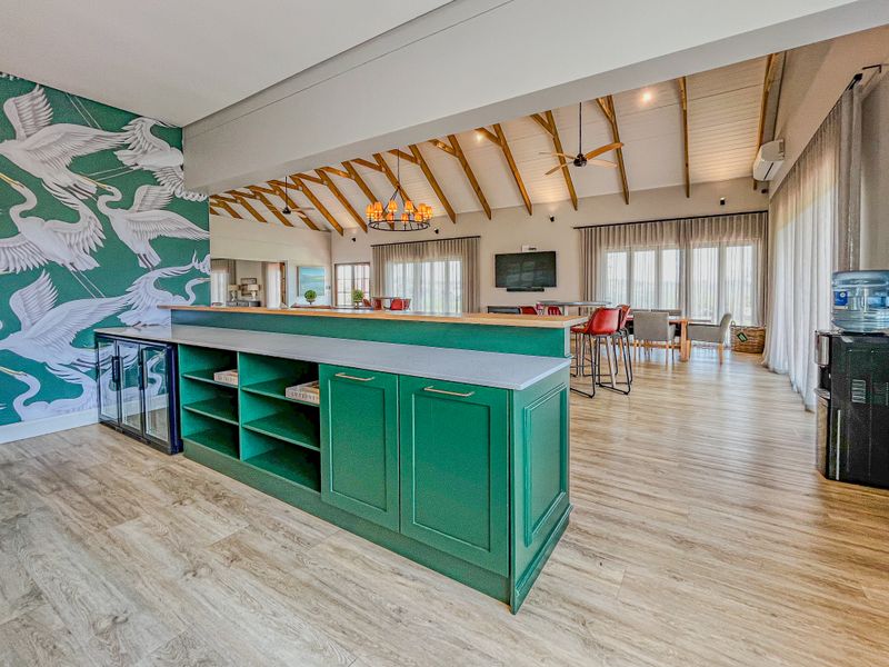 Spacious open-plan living area featuring a custom green built-in bar, exposed timber rafters, and high-quality finishes throughout.