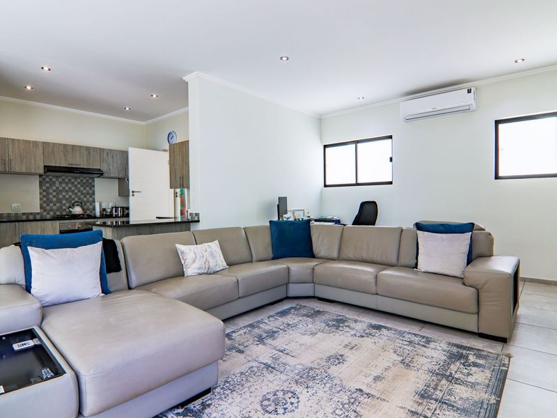 Spacious open-plan living area featuring a modern kitchen with granite countertops, tiled flooring, and an integrated air conditioning unit.