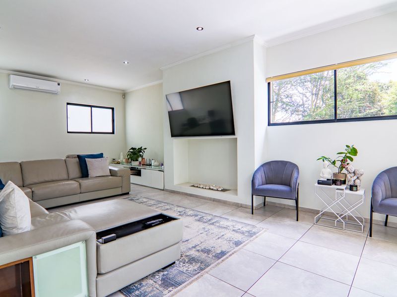 Spacious living room featuring neutral tiled flooring, recessed downlights, an air conditioning unit, and a built-in fireplace niche.