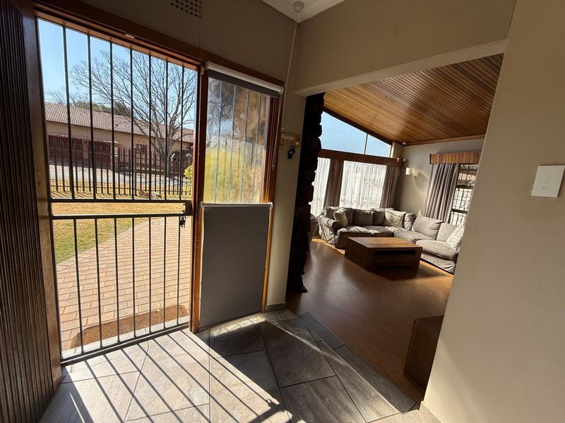 Entrance foyer featuring tiled flooring, leading into a spacious living area with timber vaulted ceilings and a stone feature wall.