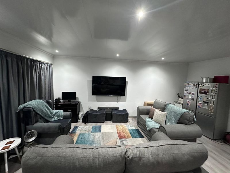 An open-plan living area featuring recessed downlighting and light-toned laminate flooring, providing a functional and versatile space for relaxation.