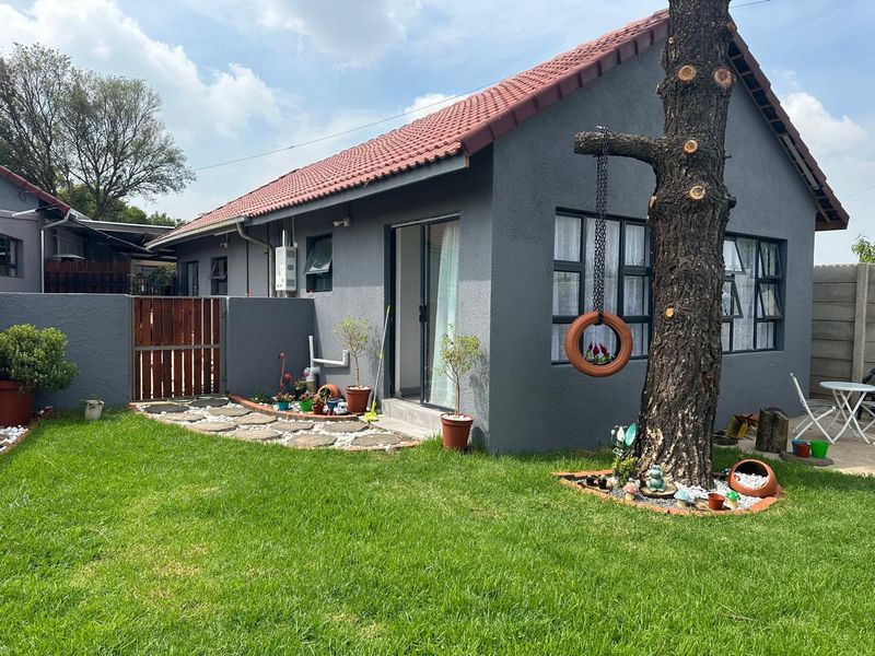 Rear view of a modern grey-painted house featuring a tiled roof, sliding glass doors, and a well-maintained garden area.