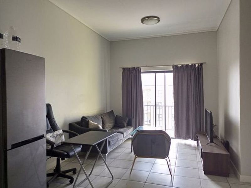 A functional living room featuring tiled flooring and a sliding glass door that provides access to a balcony.