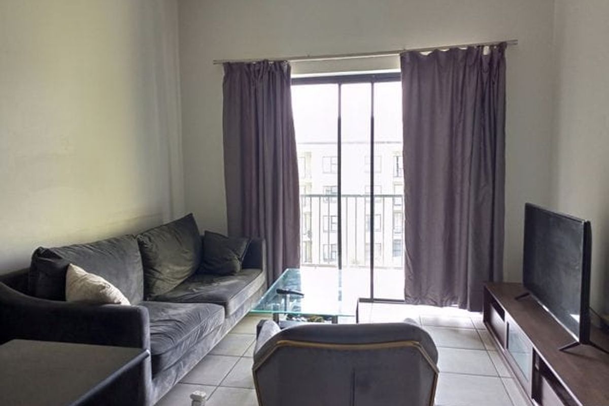 A living room featuring tiled flooring and a sliding glass door that opens to a balcony, providing natural light to the space.