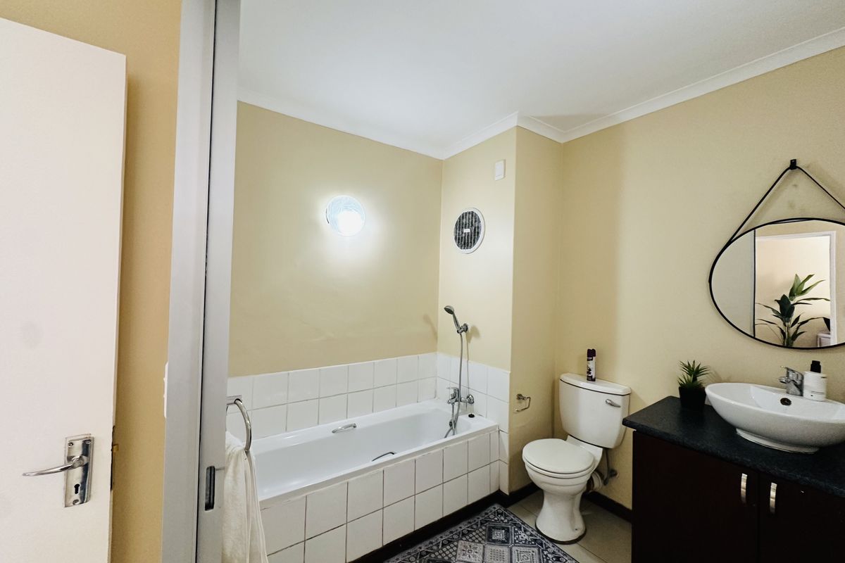 A functional bathroom featuring a tiled bathtub, a white toilet, and a dark vanity cabinet with a modern vessel sink.
