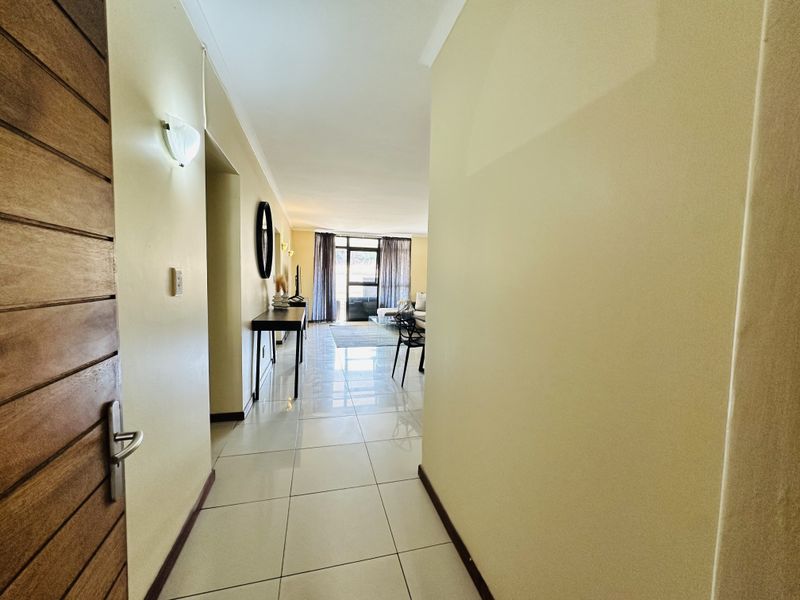 A bright entrance hallway with tiled flooring leading into an open-plan living area with natural light.