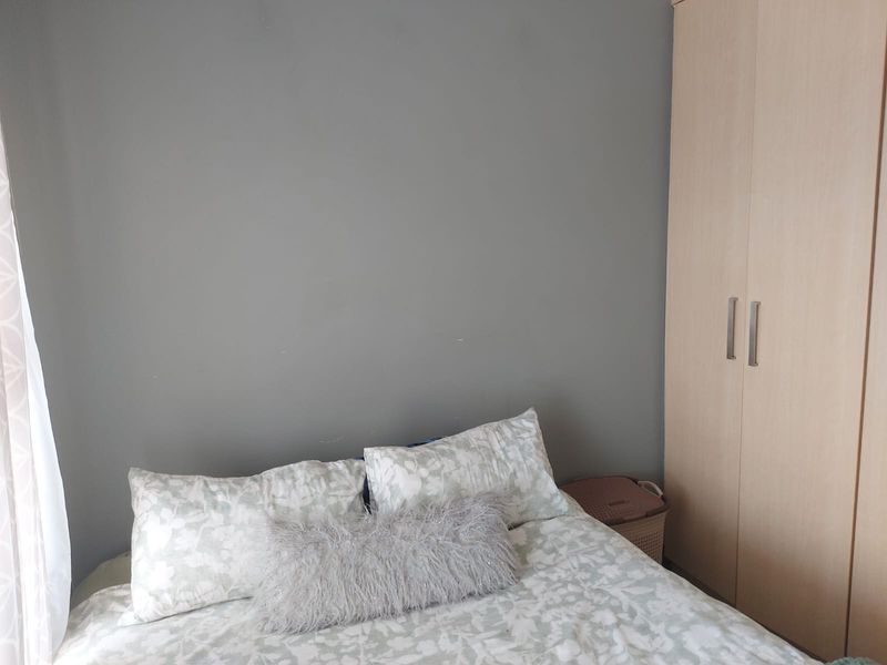 A bedroom featuring a neutral grey wall and a light wood-finish built-in wardrobe.